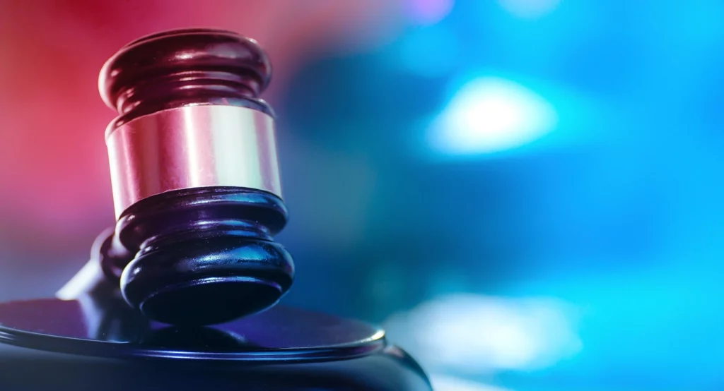 A snapshot of a gavel with police lights in the background, symbolizing the varying comparative negligence laws across different states.