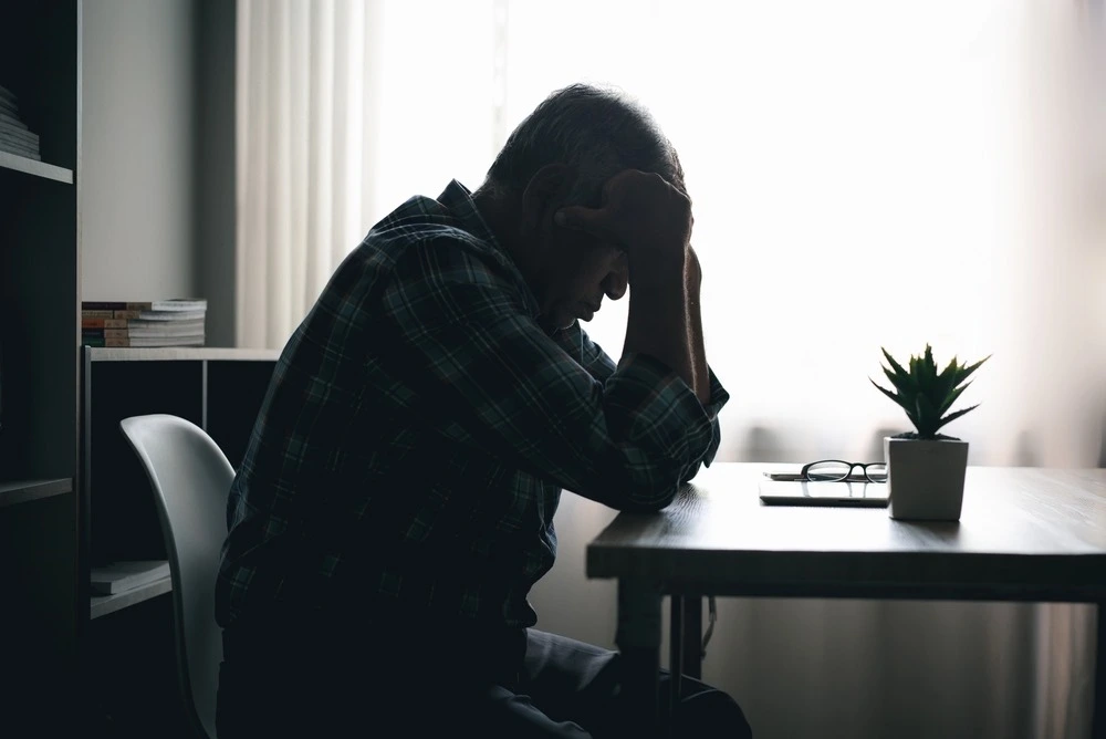 Snapshot of a person sitting in a dimly lit room, symbolizing the heavy financial toll of underinsured motorist accidents.