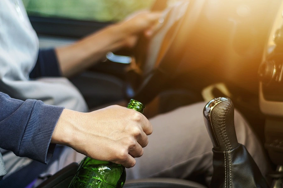 Snapshot of a person drinking while behind the wheel, representing one of the common causes of serious stop sign accidents.
